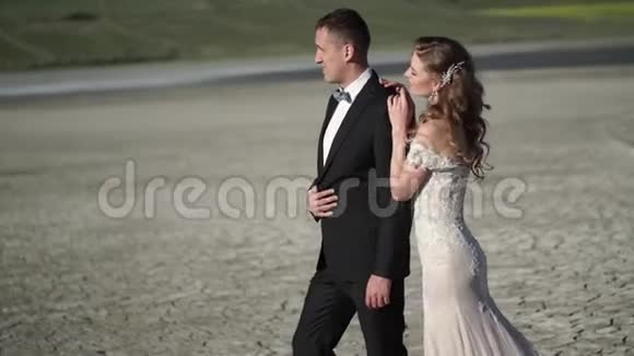 年轻漂亮的新娘穿着婚纱新郎拥抱亲吻视频的预览图