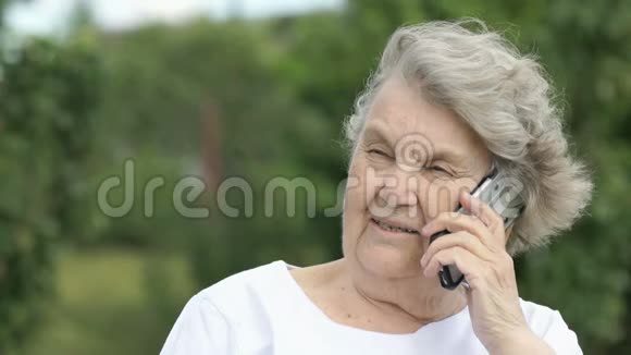 一位在户外使用智能手机聊天的老年妇女视频的预览图