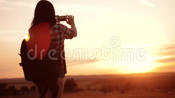hipsterhiker剪影女孩的生活方式是在手机智能手机上拍摄美丽自然日落的视频视频的预览图