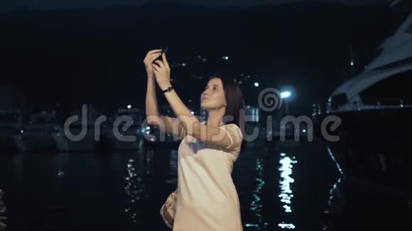 勇女用智能手机拍照时尚的夏日旅行者女性带电话户外在欧洲城市夜湾视频的预览图