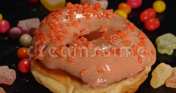 粉红色有趣的惊喜釉面甜甜圈与洒条纹焦糖糖果五颜六色的葡萄干或花生粥视频的预览图