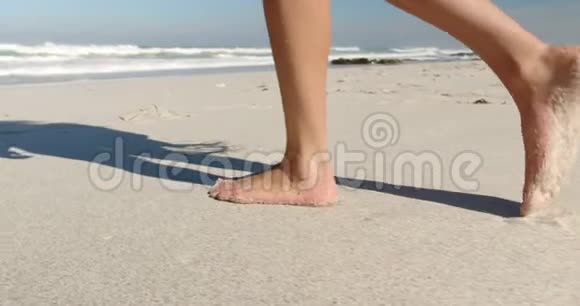 年轻女子在阳光下的海滩散步视频的预览图