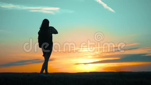 希普斯特的剪影女孩正在手机智能手机上拍摄美丽自然日落的视频视频的预览图
