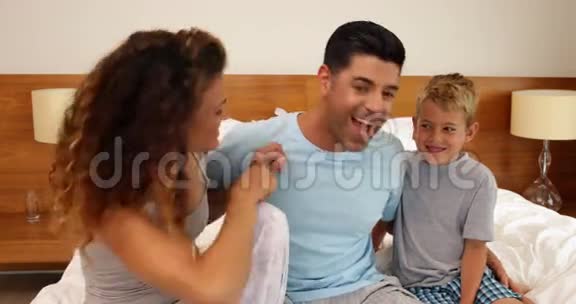 母亲和儿子在床上挠爸爸的痒痒视频的预览图