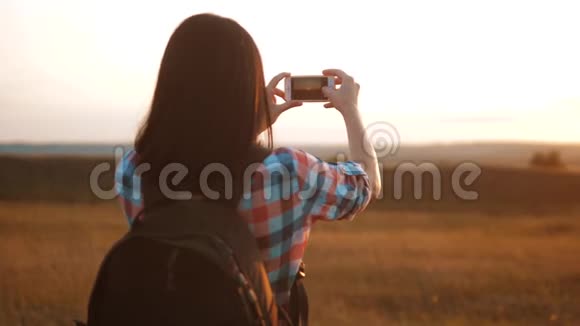 hipsterhiker剪影女孩正在手机智能手机上拍摄美丽自然日落的视频视频的预览图