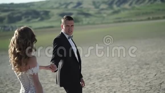 年轻漂亮的新娘穿着婚纱新郎走着视频的预览图