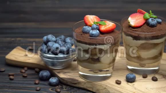 经典的提拉米苏甜点在木制背景的玻璃杯中加入蓝莓和草莓视频的预览图