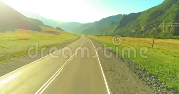 在阳光明媚的夏季早晨低空飞越山路和草地视频的预览图
