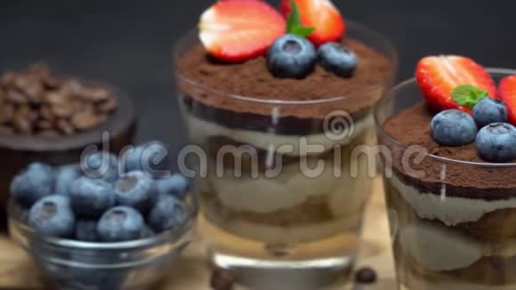 经典的提拉米苏甜点蓝莓和草莓在深色混凝土背景下的玻璃杯中视频的预览图