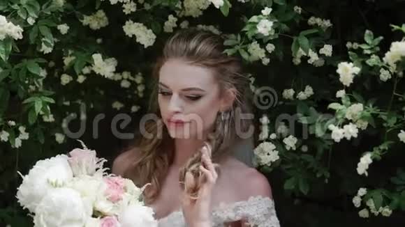 阳光明媚的一天年轻的新娘在鲜花旁边摆姿势视频的预览图