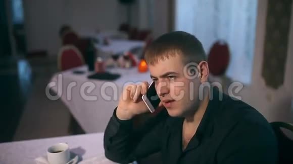 在咖啡馆的一家餐馆里一个男人在用智能手机说话视频的预览图