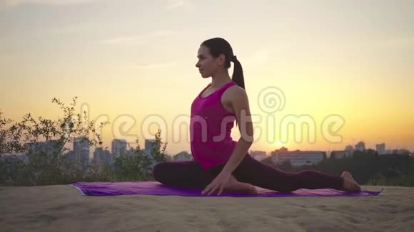 在大城市的背景下一位年轻女子在山上练习瑜伽视频的预览图