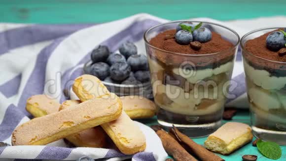经典的提拉米苏甜点在蓝色木制背景的蓝莓玻璃视频的预览图