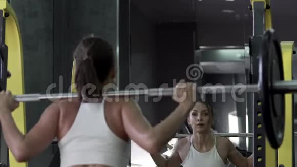 美丽的年轻女性健身模特在健身房里用烧烤训练视频的预览图