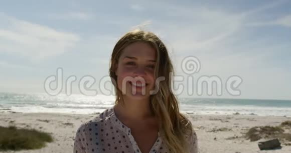 晴天站在海滩上的年轻女子4k视频的预览图
