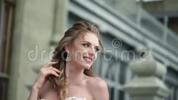 年轻的新娘在城市里摆姿势在刮风的夏日挥舞面纱视频的预览图