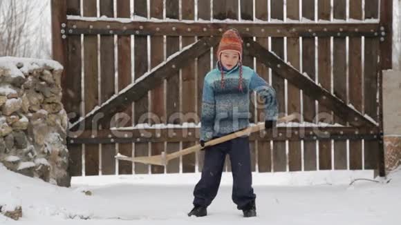 男孩在房子附近摘下雪铲冬天打扫房子附近的雪视频的预览图