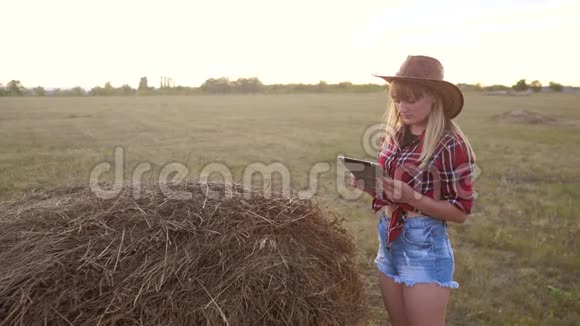 智慧农业慢动作视频概念女孩农学家在干草堆里拿着平板电脑触摸板电脑正在学习视频的预览图
