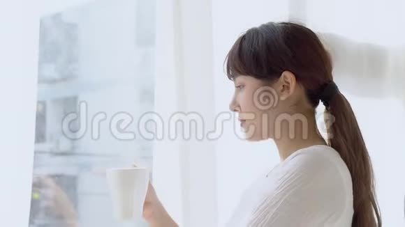 美丽的肖像年轻的亚洲女人微笑喝一杯咖啡放松视频的预览图