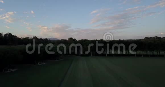 日落时飞越丘陵和马球场视频的预览图