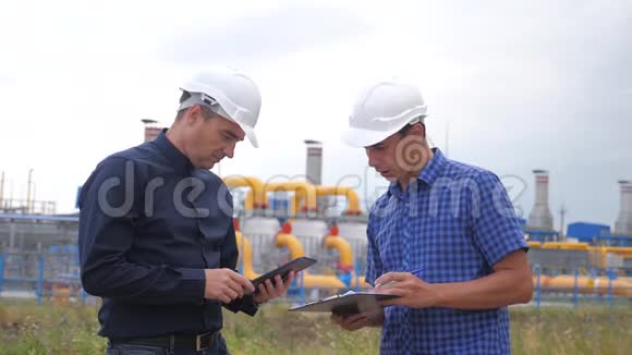 团队合作工业煤气生产站的概念慢动作录像两名戴头盔的工程师正在与视频的预览图