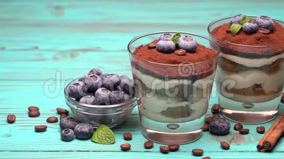 经典的提拉米苏甜点在蓝色木制背景的蓝莓玻璃视频的预览图
