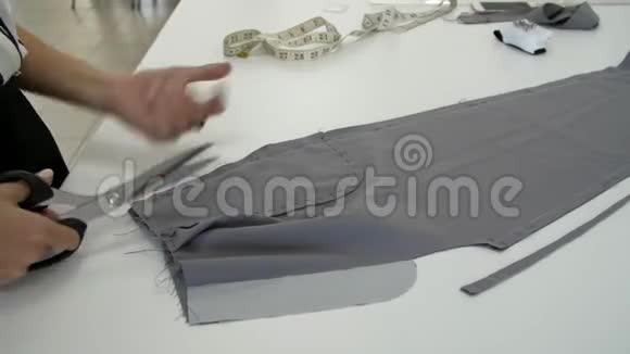 女性的双手用鞘把一块灰色的布割下来视频的预览图