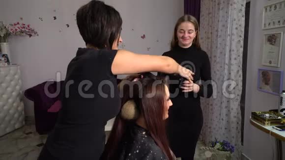 美容院理发店的年轻漂亮女孩理发师给女孩做发型布鲁内特在美容院视频的预览图