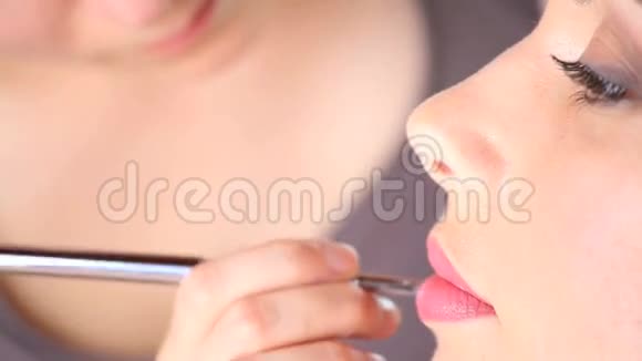 化妆师用刷子在模特嘴唇上涂口红视频的预览图