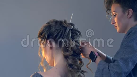 化妆师和理发师正在准备婚礼前的新娘发型短而时尚的发型设计师化妆视频的预览图