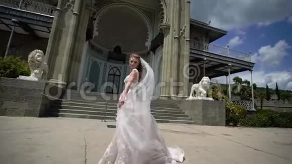 年轻的新娘在城市里摆姿势在刮风的夏日挥舞面纱视频的预览图