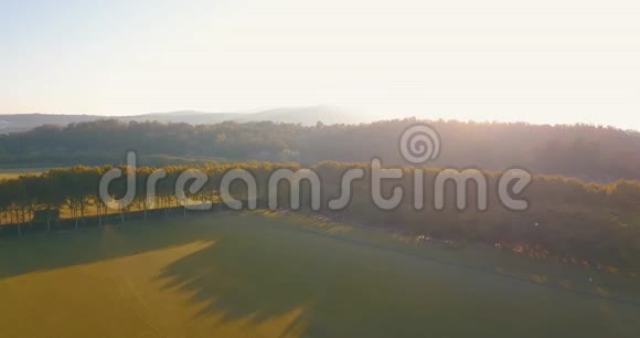 高空飞行低空飞行日落时飞越丘陵和马球场视频的预览图
