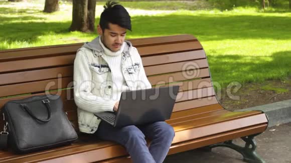 坐在公园里用笔记本电脑工作的人视频的预览图