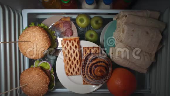 平躺的手在晚上拿食物放在冰箱的架子上视频的预览图