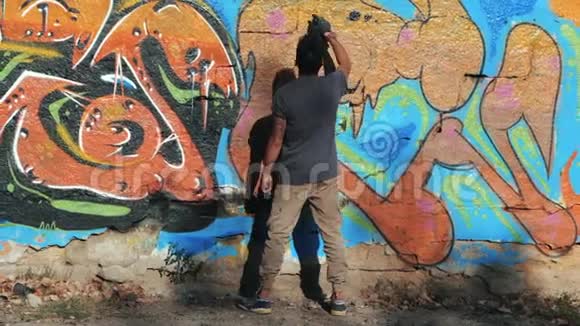 涂鸦艺术家画与气溶胶带喷雾瓶的人动作缓慢年轻的城市画家画彩色涂鸦视频的预览图