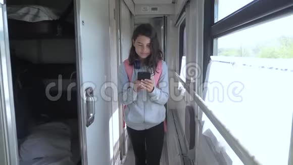 十几岁的女孩带着背包和智能手机在火车车厢里散步旅游运输铁路概念视频的预览图