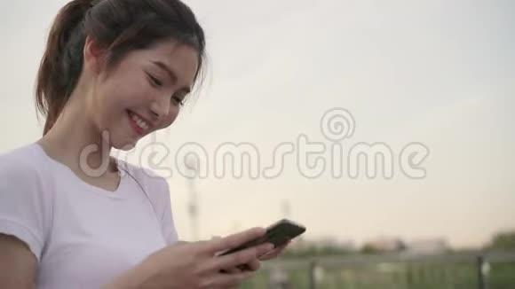 性格开朗的亚洲旅游博客女性在市中心大街上散步时在智能手机上使用触摸屏技术视频的预览图