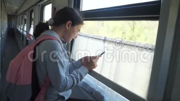 带背包的少女旅行者站在火车车窗旁车上有一部智能手机旅费视频的预览图
