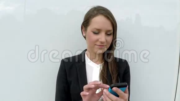 商务女性站在白色玻璃墙边带着智能手机视频的预览图