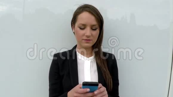 商务女性站在白色玻璃墙边带着智能手机视频的预览图