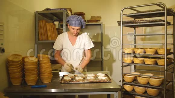 面包师为面包在面团上手工切开面包的制造面包店视频的预览图