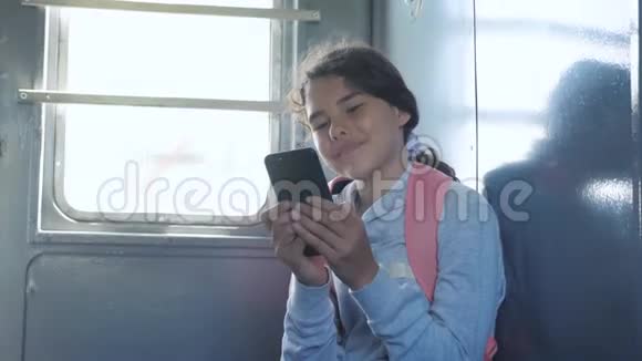 年轻的女孩旅行者带着一个背包坐在装有智能手机的车窗上的背包上旅游线路视频的预览图