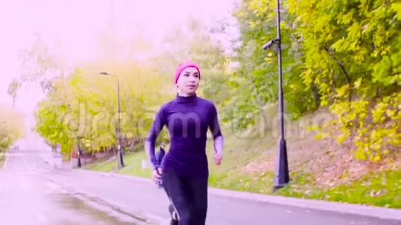 年轻的女人在公园里跑步秋天视频的预览图