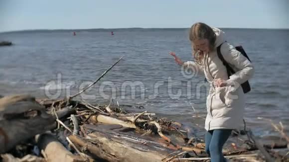 美丽的年轻女子沿着河岸散步收集干涸的树枝视频的预览图
