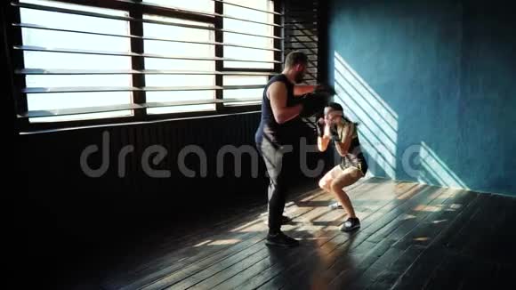 在健身房和拳击教练一起训练白人女拳击手视频的预览图