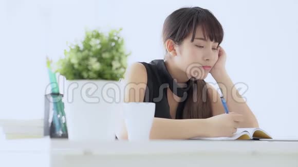 美丽的亚洲女人微笑着坐在客厅里学习在家写笔记本视频的预览图