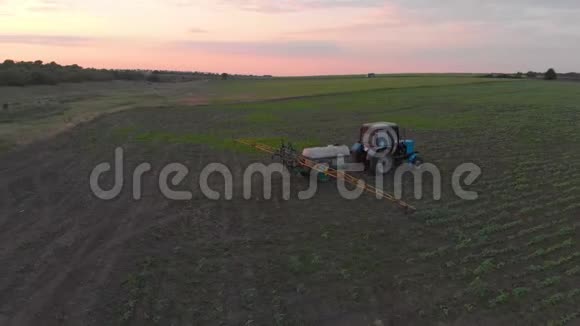 日落时用新鲜的年轻的土豆灌溉田间拖拉机的鸟瞰图视频的预览图