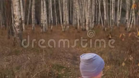 一个高加索儿童在秋天公园骑自行车走路小女孩在森林里走着黑色的橙色循环孩子是干的视频的预览图
