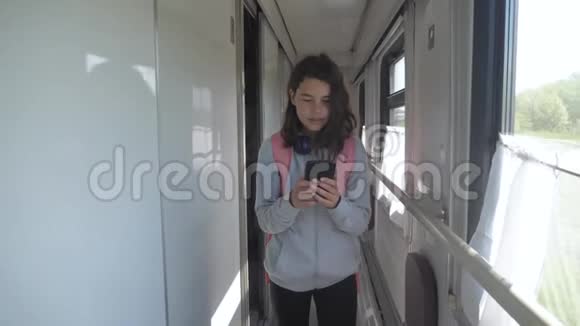 十几岁的女孩带着背包和智能手机在火车车厢里散步旅游交通铁路生活视频的预览图