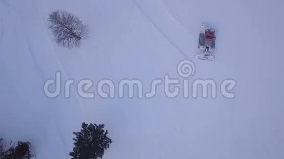 在准备滑雪场时在雪猫上方飞行视频的预览图